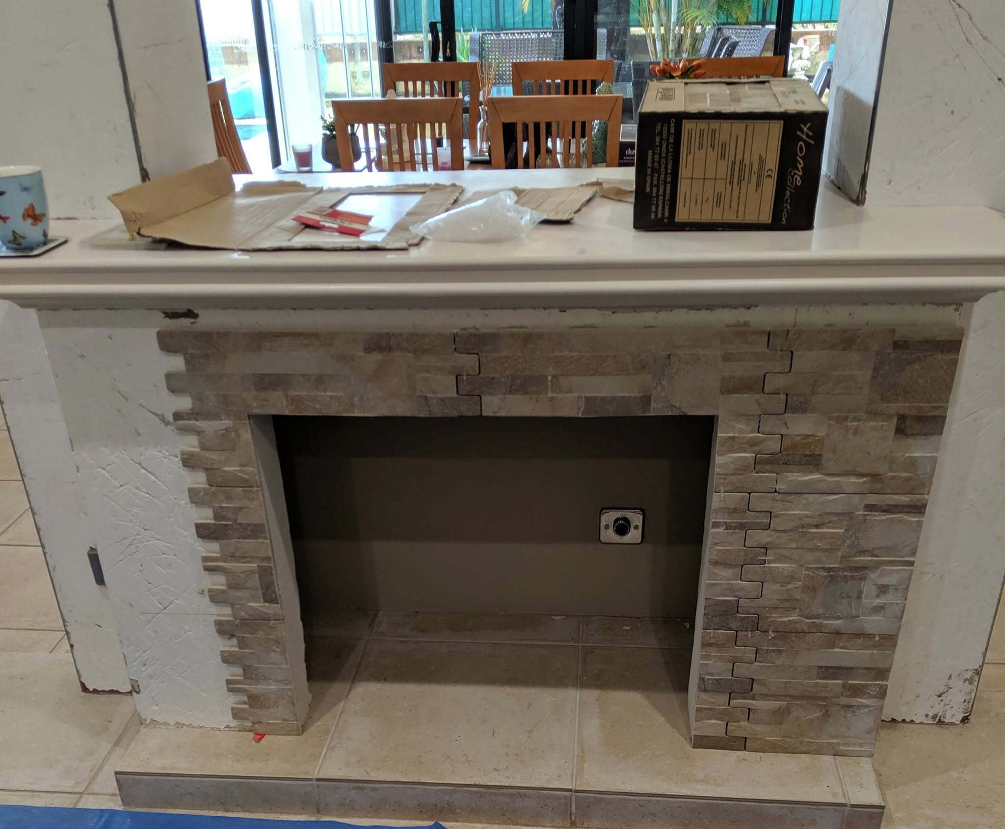 Fireplace surround finished in split-face stacked stone tile, with a painted timber mantel