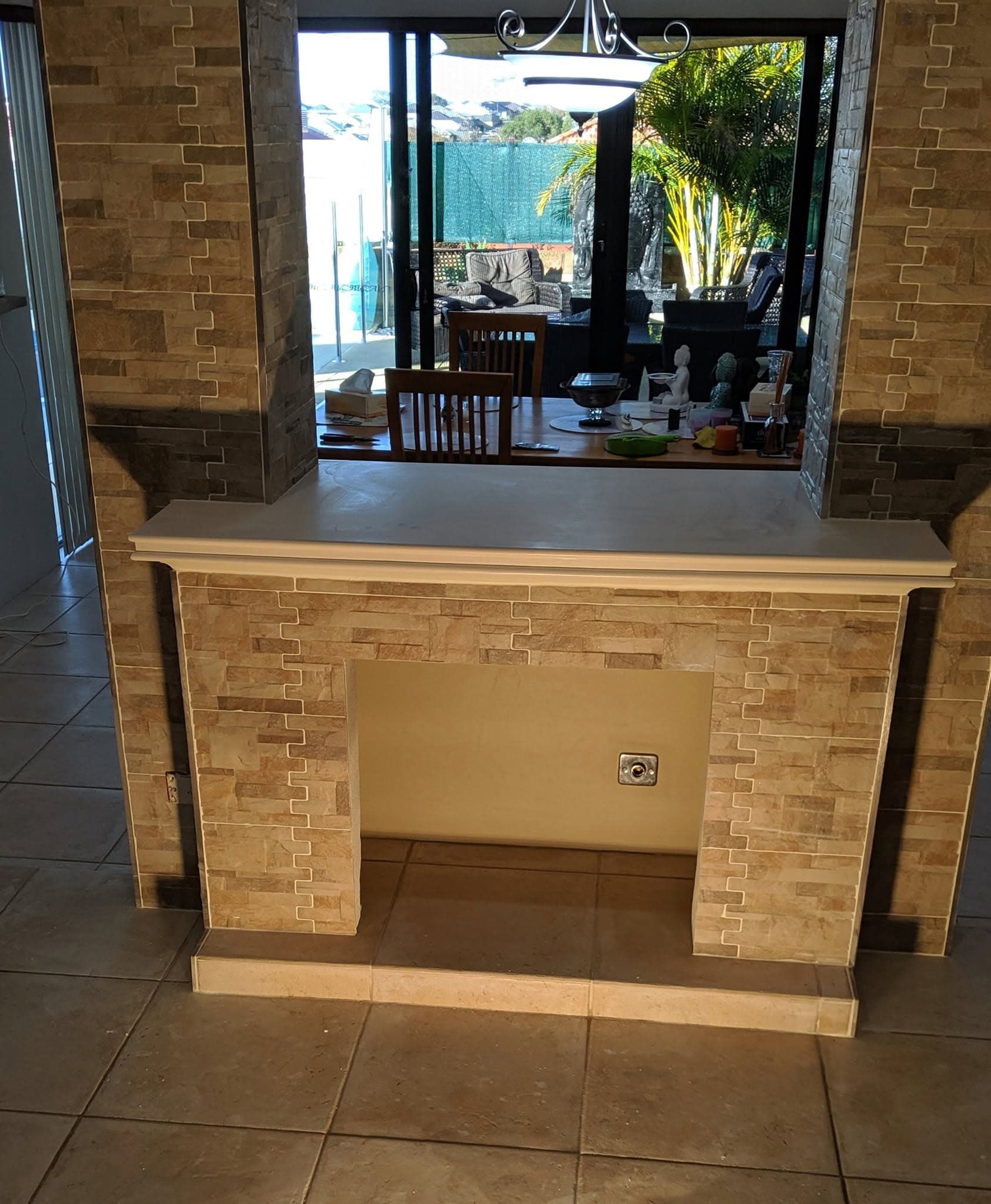 Double-sided fireplace alcove finished in split-face stacked stone tile, with a stone hearth and mantel