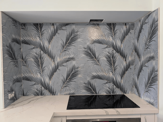 Kitchen alcove with a bold grey palm-leaf pattern tile splashback behind an induction cooktop