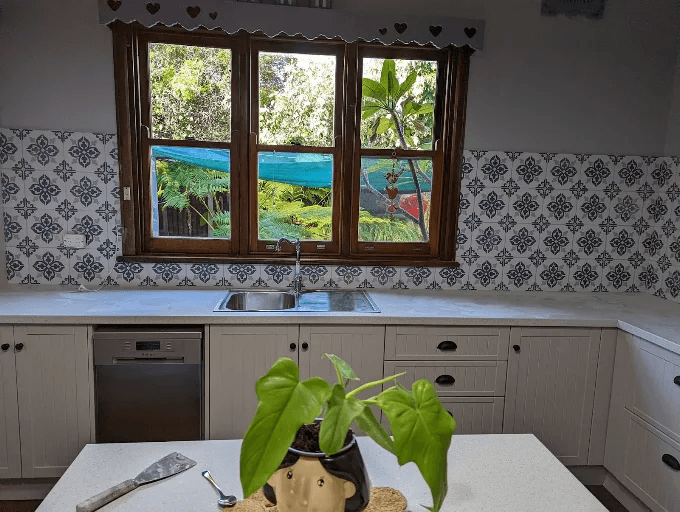 Black and white patterned tile splashback around a timber-framed kitchen window above the sink
